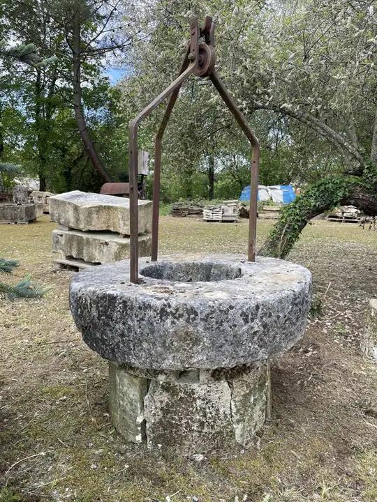Ancienne margelle de puits monolithe et sa ferraille posée sur deux rangs de pierres dures