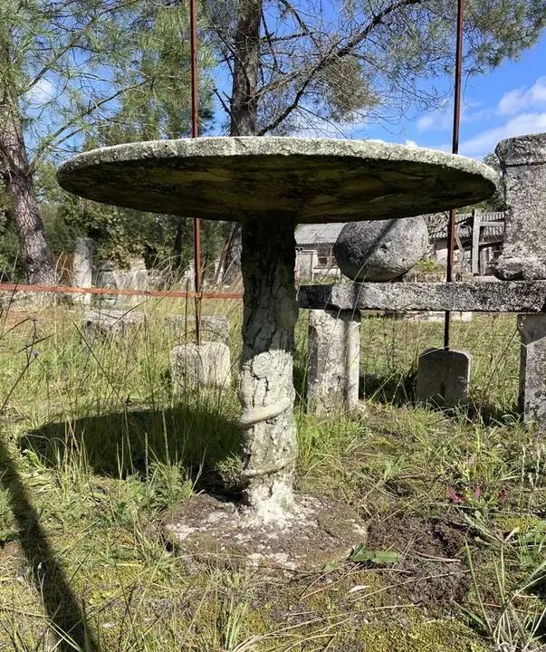 Table de jardin ronde avec pietement recouvert de ciment au décor de feuillage