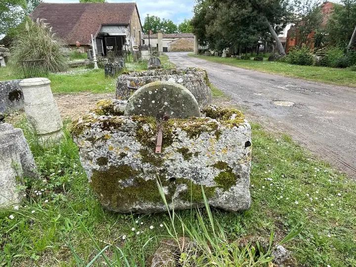 Ancienne meule á eau et son support en pierre creusé. Meule á aiguiser les couteaux accionnée par une manivelle en fer forgée