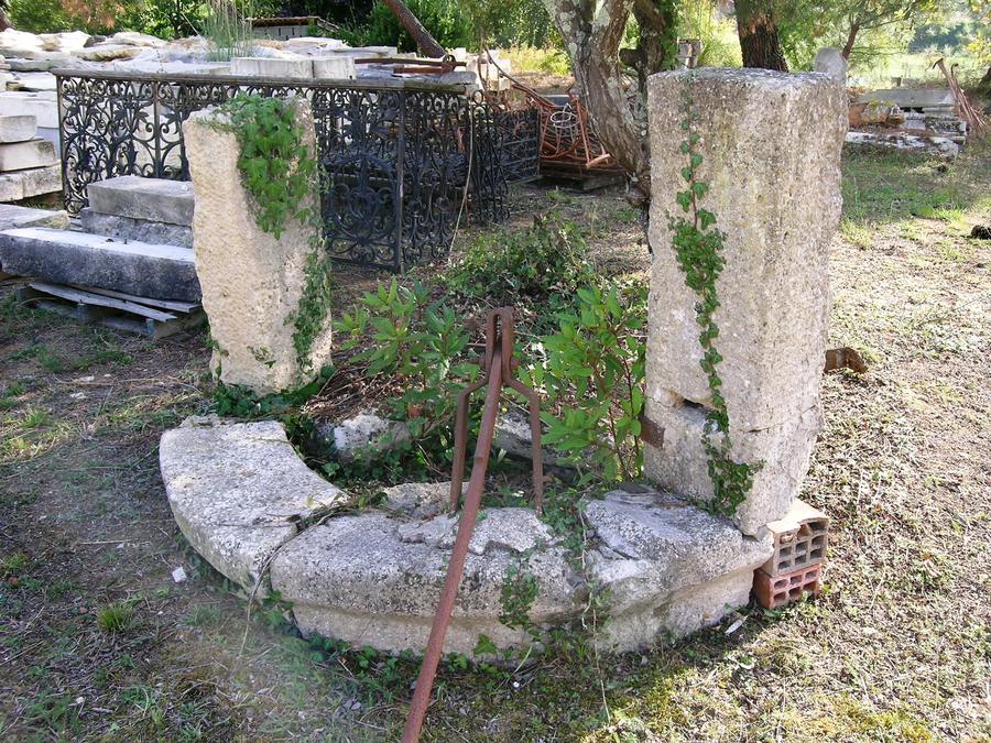 Margelle de puits integrée dans un mur avec sa pierre de toit